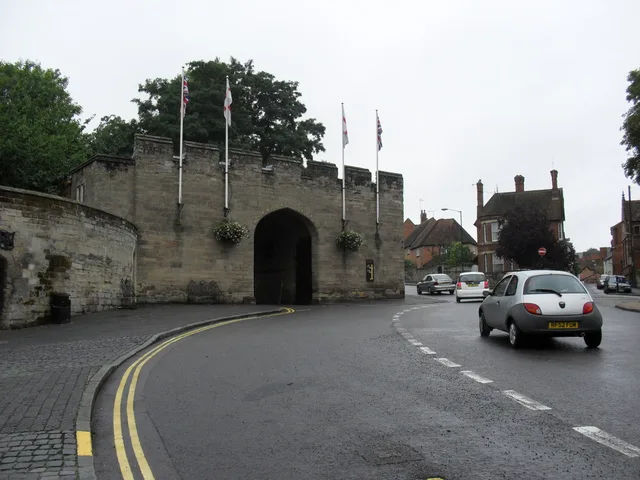 A stone entrance and towers at Warwick Castle seen from the street.