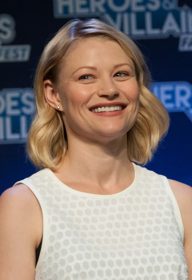 Smiling woman with shoulder-length blonde hair in a white sleeveless top at a fan convention panel