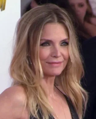 Head and shoulders photograph of a woman with long wavy blonde hair, smiling slightly and looking off to one side.