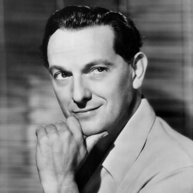 Black and white publicity portrait of Joseph Schildkraut with slicked dark hair, resting his chin on his fist and smiling slightly.