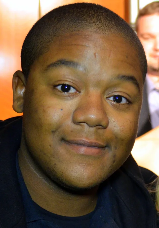 Close portrait of Kyle Massey with short dark hair, giving a slight smile to the camera.
