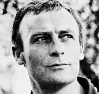 Black and white close-up photograph of a younger man glancing to the side, with tousled hair, taken outdoors.