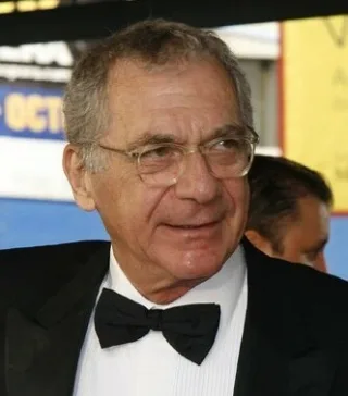 Close photograph of Sydney Pollack, an older man with grey hair and round glasses, wearing a black dinner jacket and bow tie.