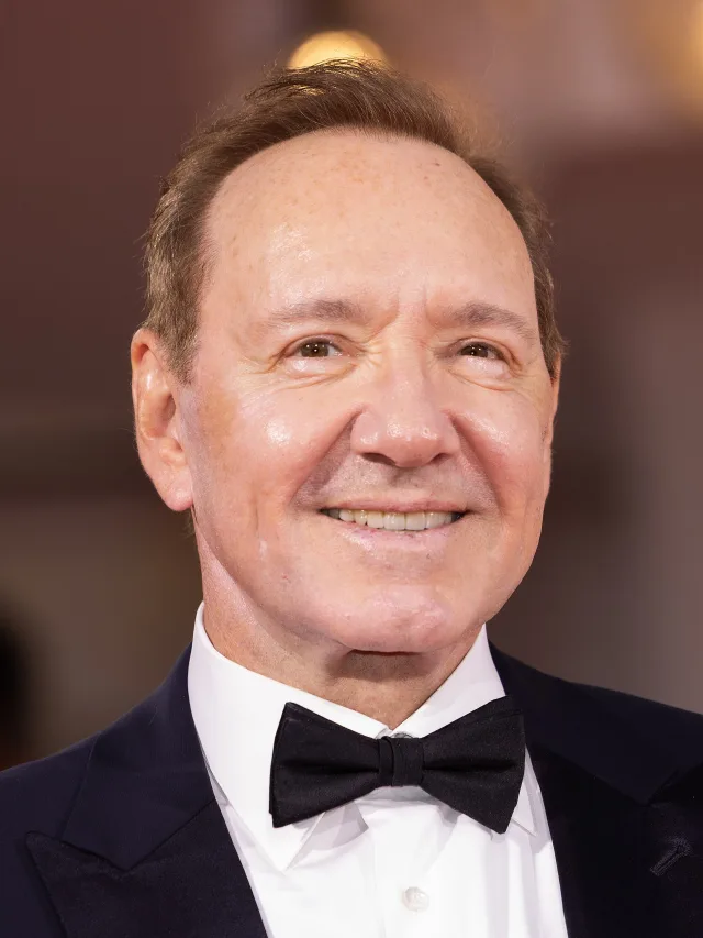 Close-up portrait of Kevin Spacey smiling, wearing a dark tuxedo jacket, white shirt and black bow tie.