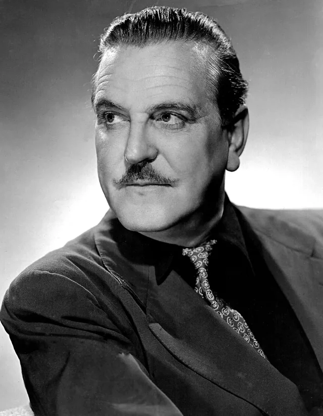 Black and white studio portrait of Frank Morgan with a moustache and slicked-back hair, glancing to one side in a dark jacket and patterned tie.