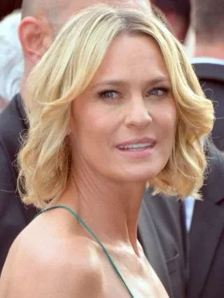 Close portrait of Robin Wright, a woman with wavy shoulder-length blonde hair, glancing to one side.