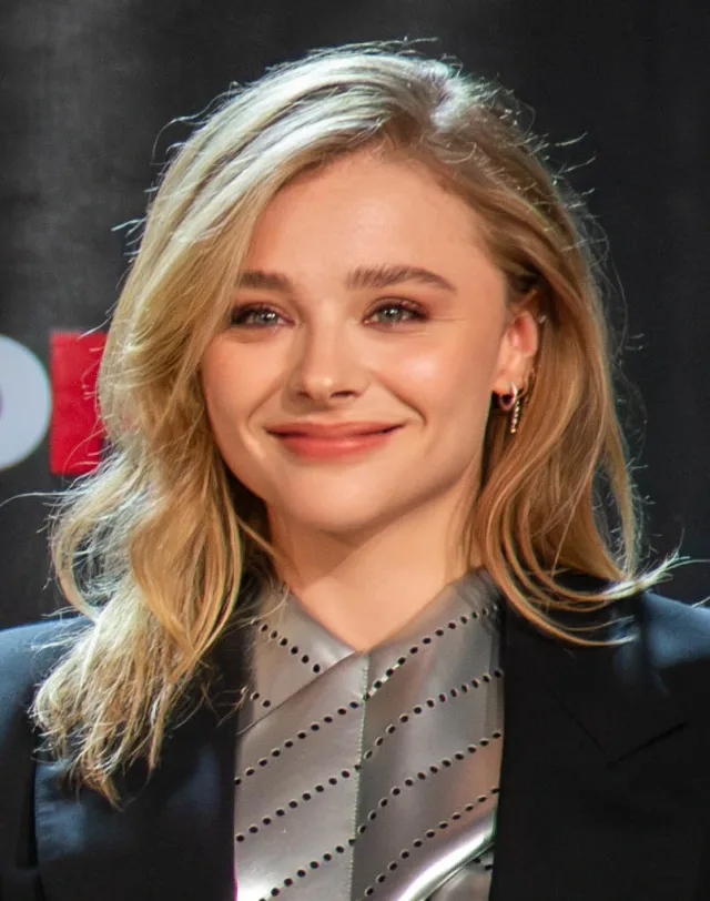 Head and shoulders photograph of a smiling young woman with shoulder-length blonde hair, in a dark jacket with a silver top.