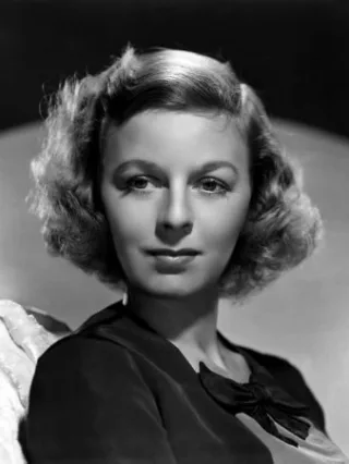 Black and white studio portrait of Margaret Sullavan with short wavy hair, in a dark top with a bow at the neckline.
