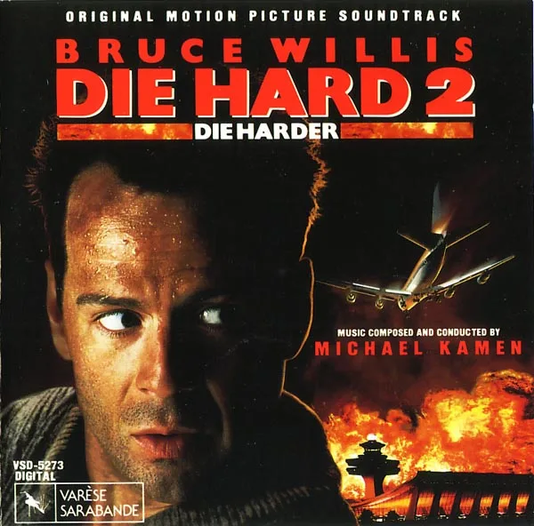 Album cover with a close-up of a man's face glancing sideways, a burning airliner above a fiery airport tower, and red and white lettering on a dark ground.